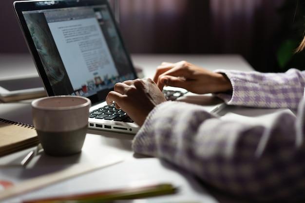 Mãos escrevendo no teclado de um laptop, com uma xícara de café ao lado. O cenário representa o dia a dia de um profissional de copy, que transforma palavras em estratégias de marketing eficazes.