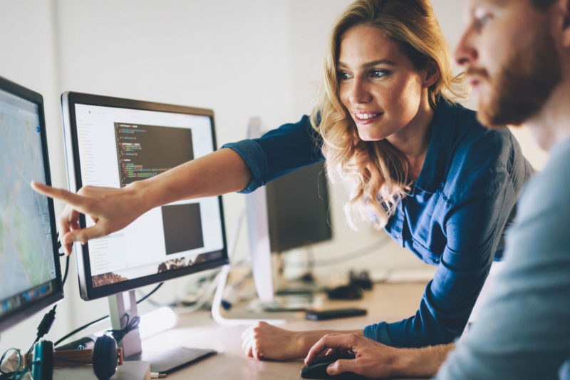 Profissionais colaborando em estratégias de marketing digital, com foco em análise de dados e planejamento em tempo real usando computadores.