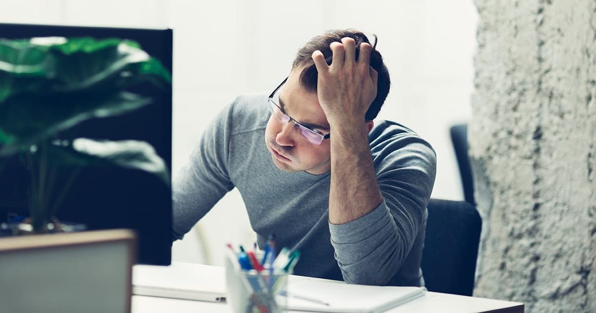 Homem frustrado diante de um computador, representando os desafios e dificuldades na gestão do funil de vendas, especialmente na conversão de leads e otimização de processos.