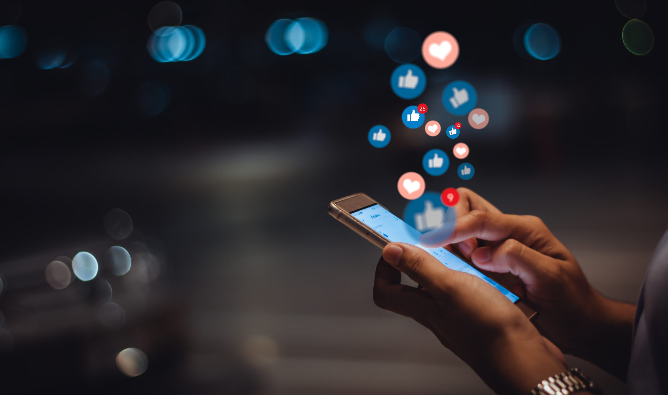 Pessoa usando um smartphone à noite, com ícones flutuantes de curtidas, corações e notificações representando interações em redes sociais, simbolizando o engajamento e a influência das estratégias de social media.