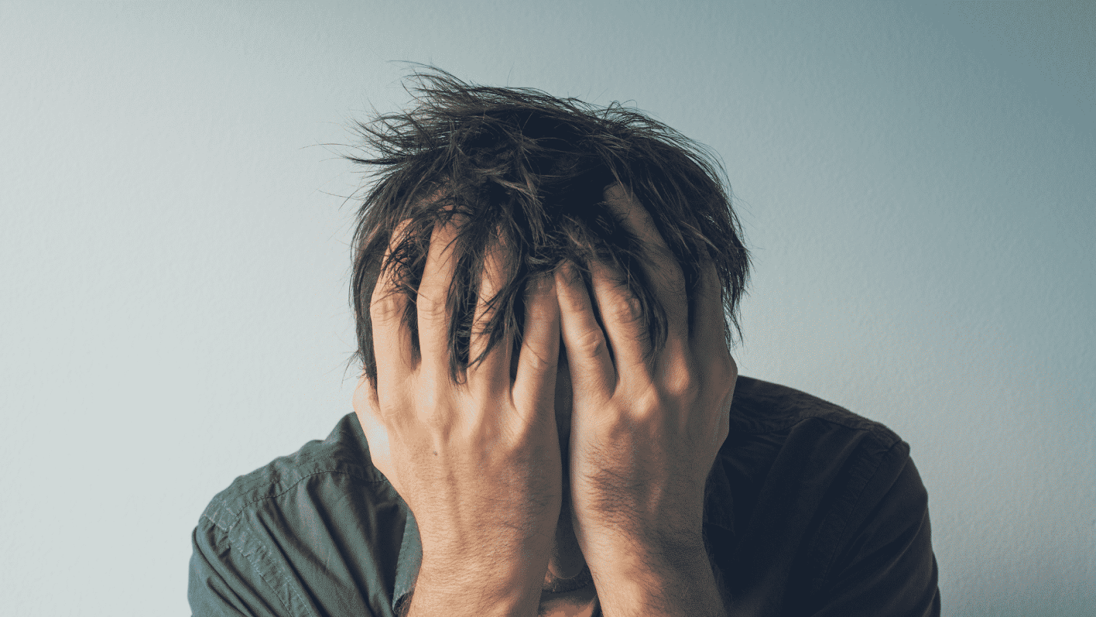 Um homem frustrado com as mãos no rosto, representando a dificuldade e o estresse de não conseguir aumentar o "Alcance no Instagram". A imagem transmite a sensação de desespero ao tentar melhorar a visibilidade online.