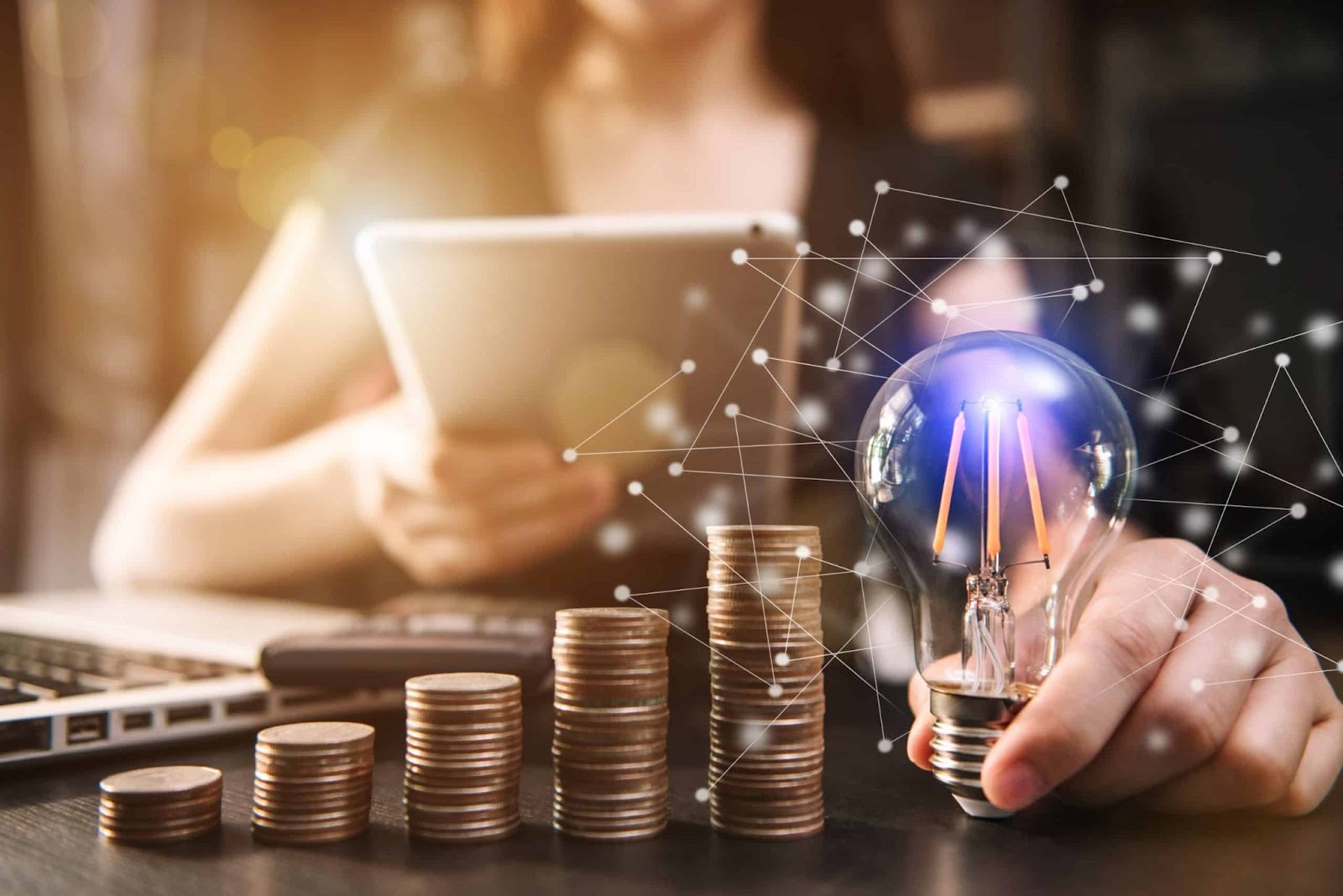 Linhas e pontos luminosos conectam a lâmpada às pilhas de moedas, ilustrando como ideias inovadoras, baseadas na compreensão do consumidor (neurovendas), podem levar ao sucesso financeiro e ao aumento das vendas. Uma calculadora e um laptop também estão parcialmente visíveis na mesa, reforçando o conceito de análise e estratégia nos negócios.