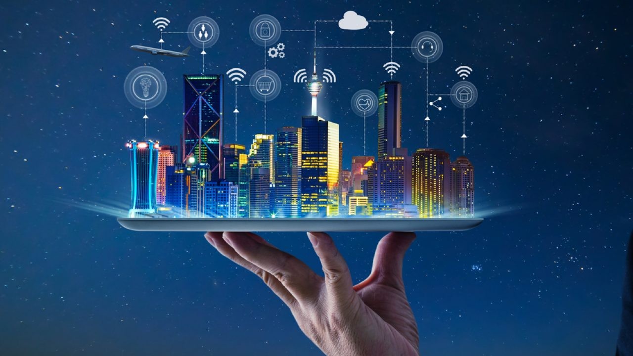 Uma mão segura um tablet que projeta uma cidade futurista com edifícios iluminados, repleta de ícones de tecnologia e conexão Wi-Fi flutuando, simbolizando a velocidade do site e a tecnologia digital.